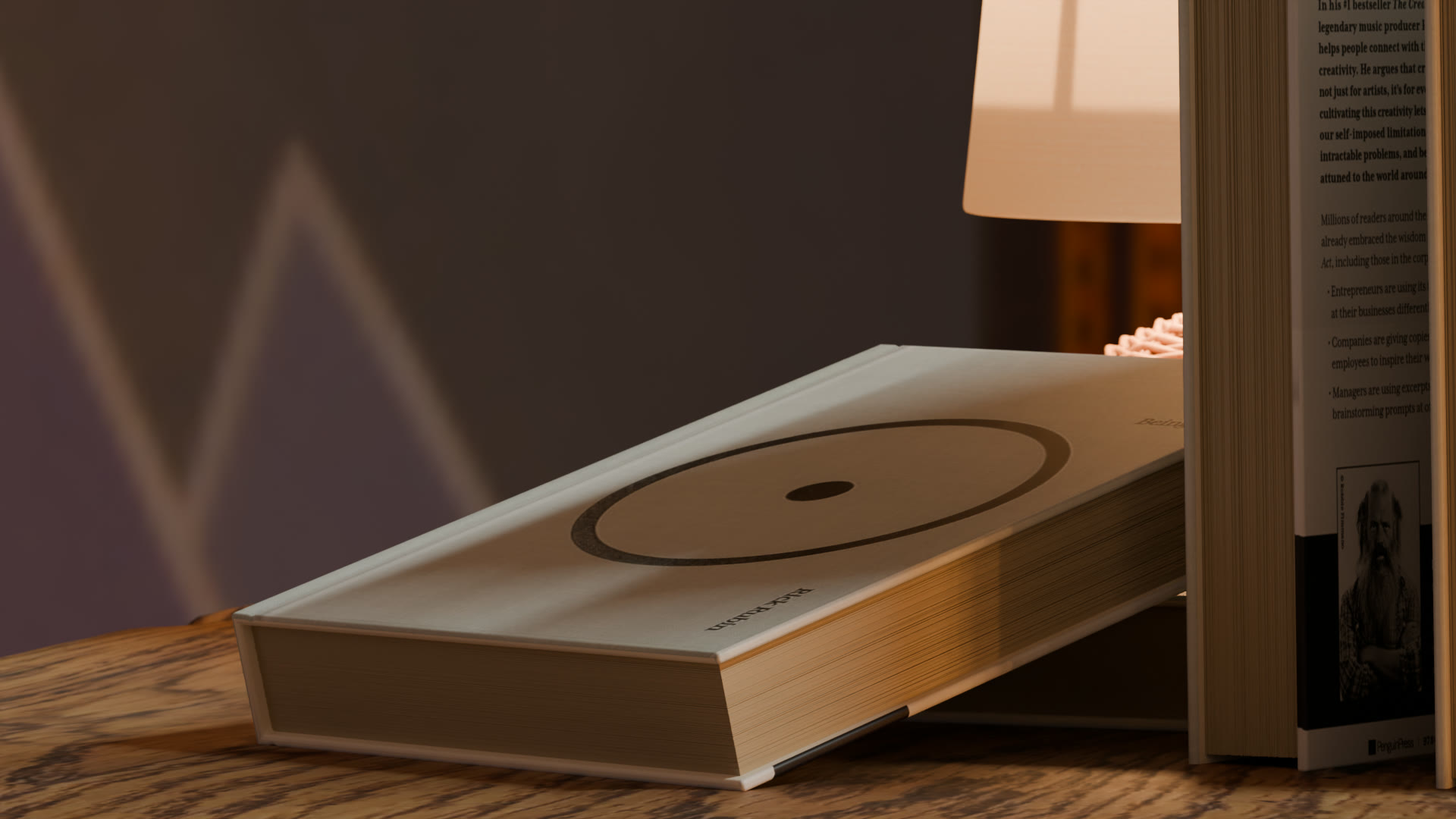A hardcover lying flat against a standing book, under lamplight