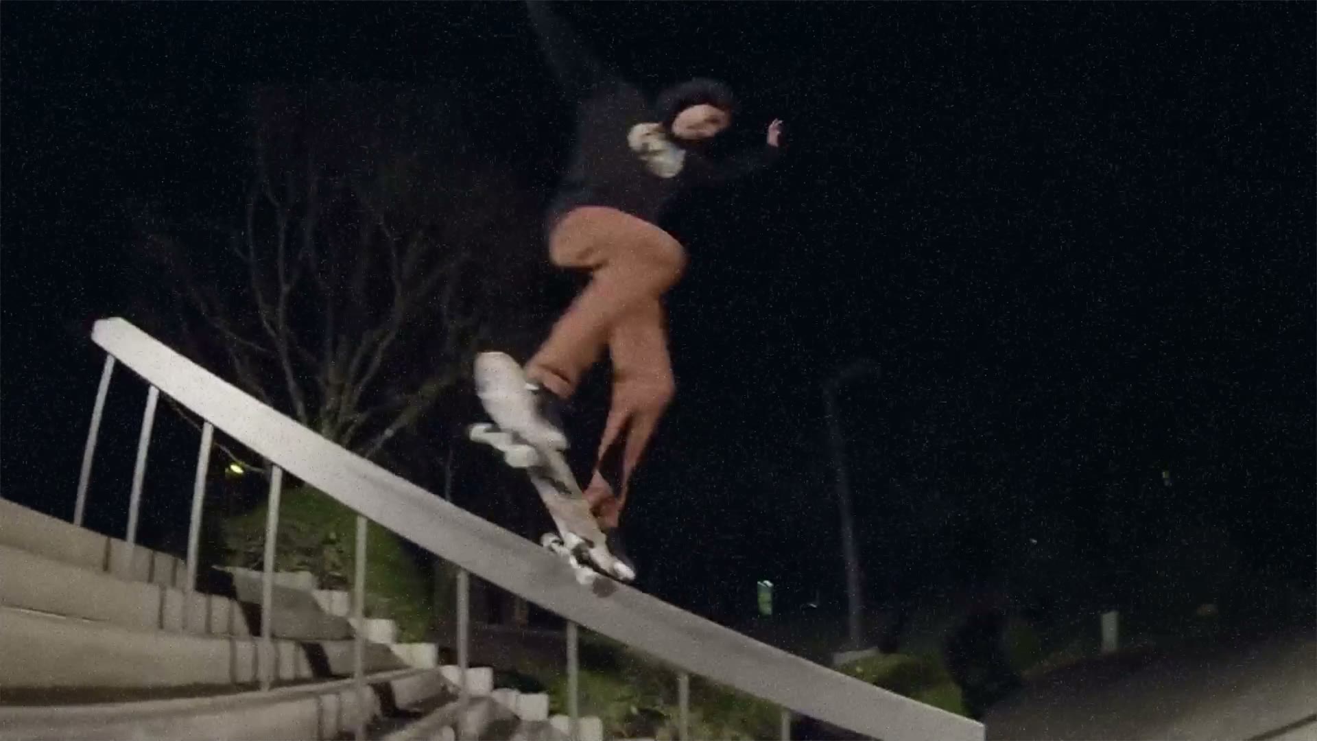 A skater grinding a handrail at night